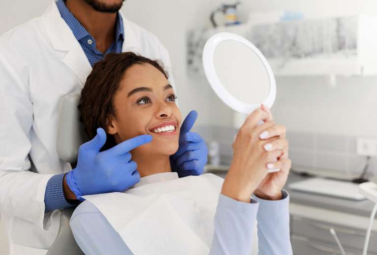 Patient checking smile in mirror for full mouth reconstruction signs